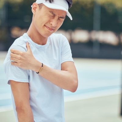 Tennis arm, man and pain on the court while playing competitive and intense game workout outside. Inflammation, accident and injury at sports training practice with asian athlete holding muscle